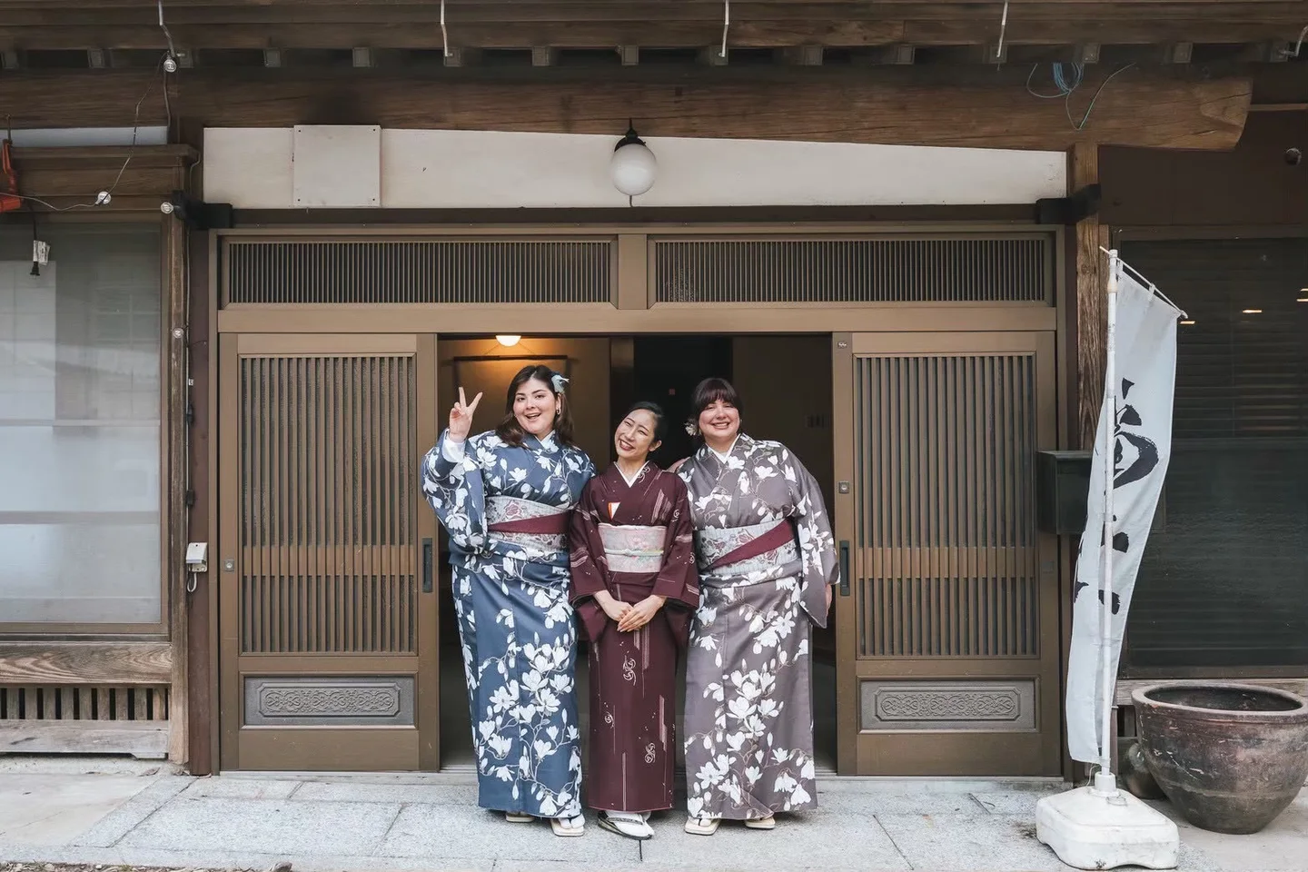 Three people in kimono sharing a moment at the entrance to Fukuwatari Tei