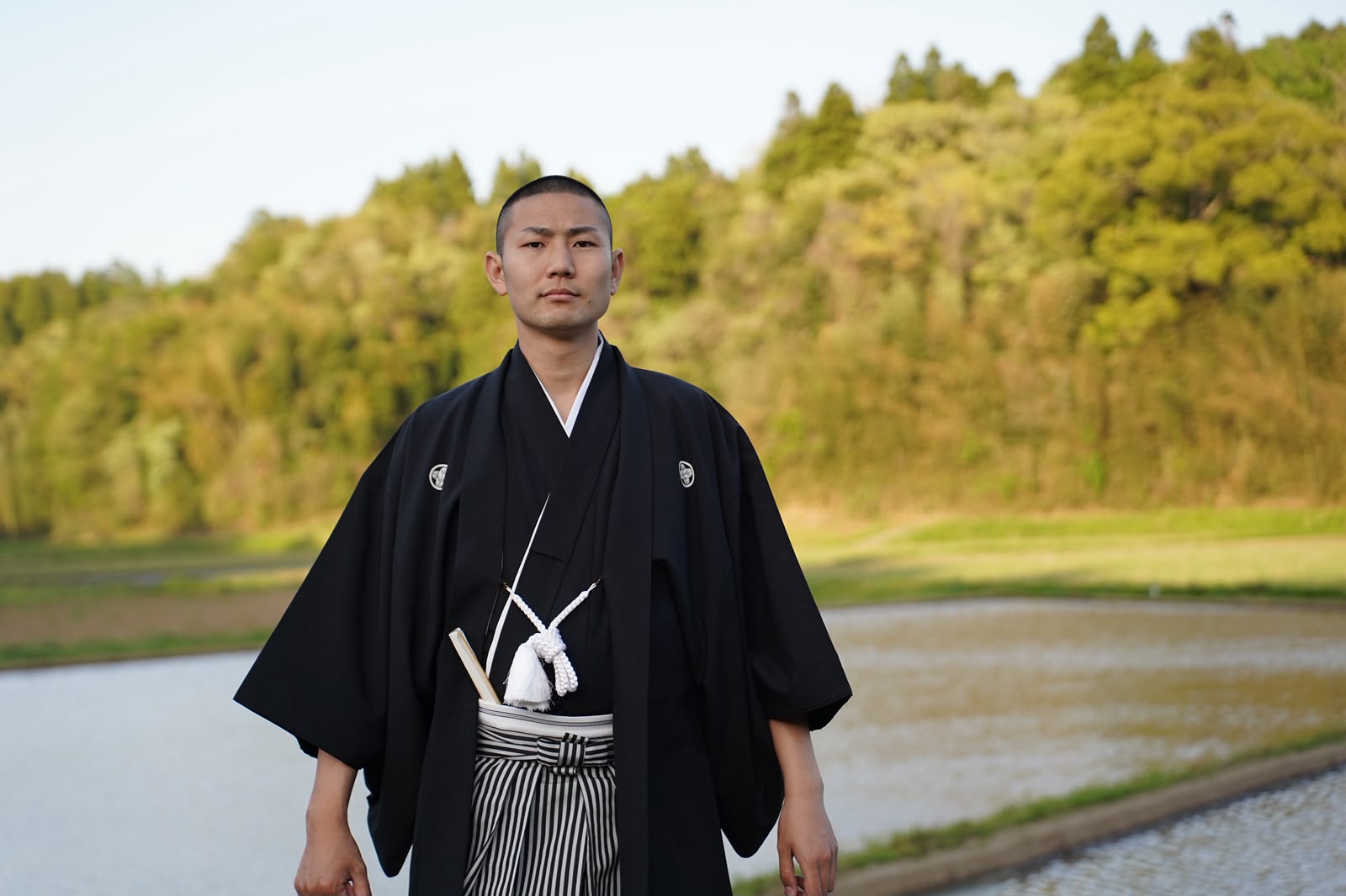 Yoshifuku Hirata in formal Japanese dress beside the fields